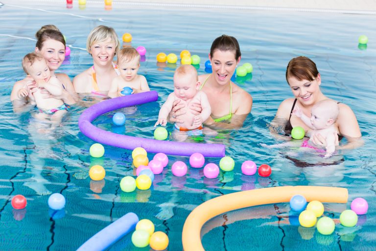 Mütter und Babys spielen gemeinsam im flachen Wasser
