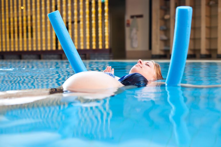 Frau mit Poolnudel im Wasser