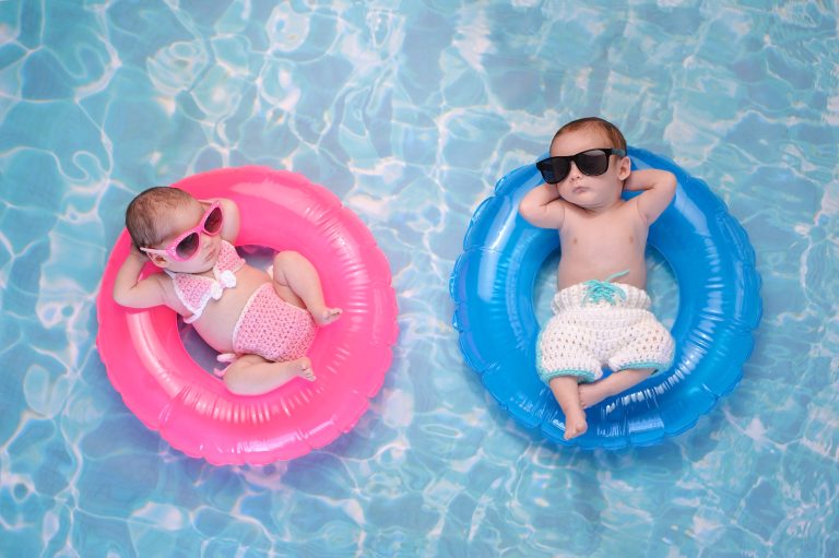 Zwei Kleinkinder liegen mit Schwimmhilfen im Wasser